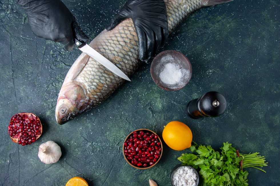 Показан процесс начала подготовки чистки рыбы, вокруг стоят ингредиенты для готовки.